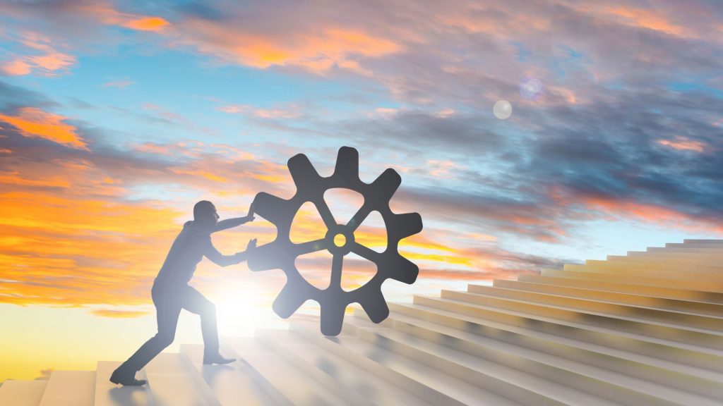 Person pushing a gear uphill